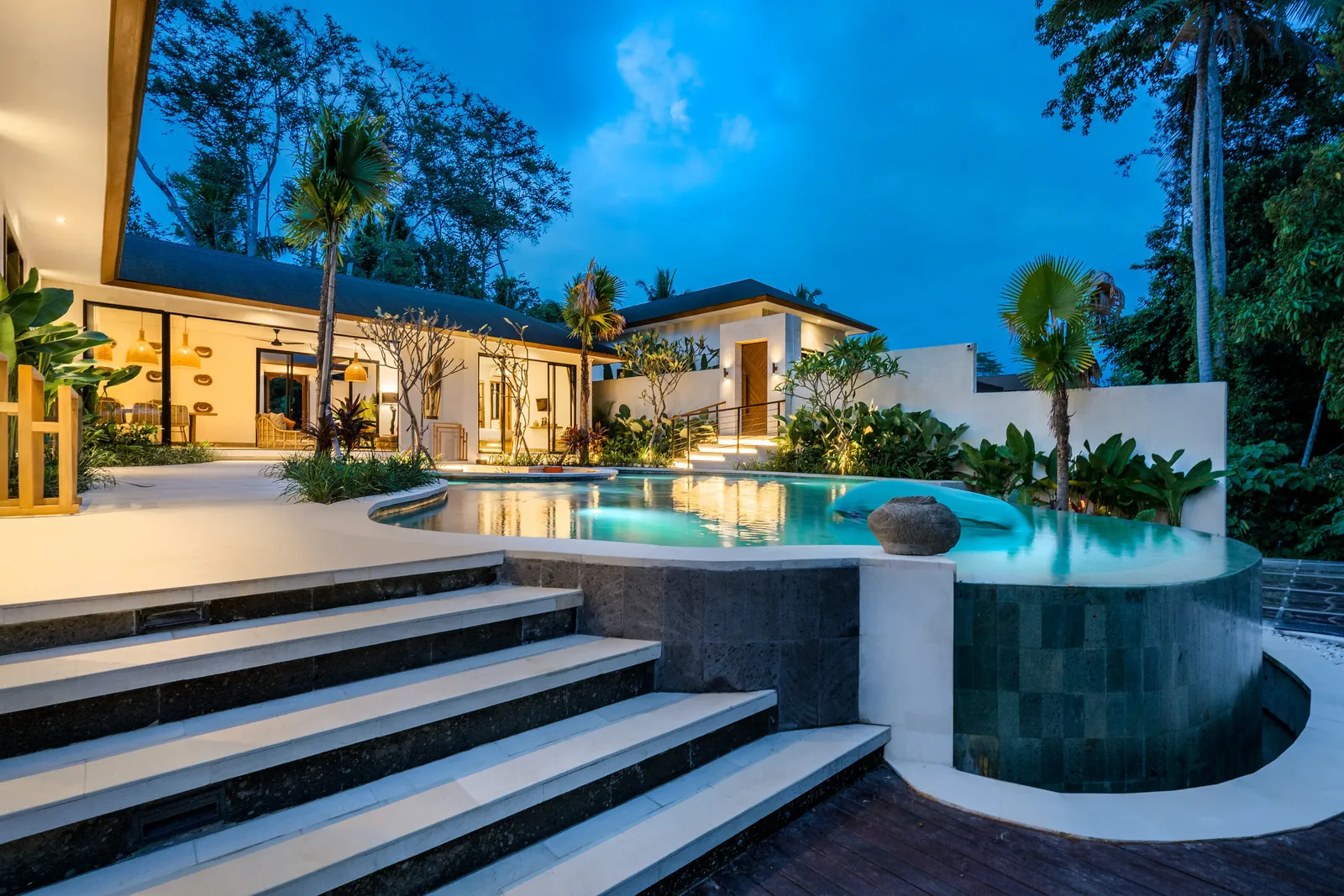 The pool at night, steps down to the water, the house lit
